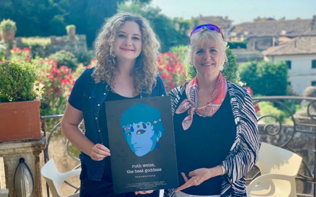 Picture of Melody and Elisabeth in Asolo Italy holding up the poster of ruth weiss the beat goddess for the premiere
